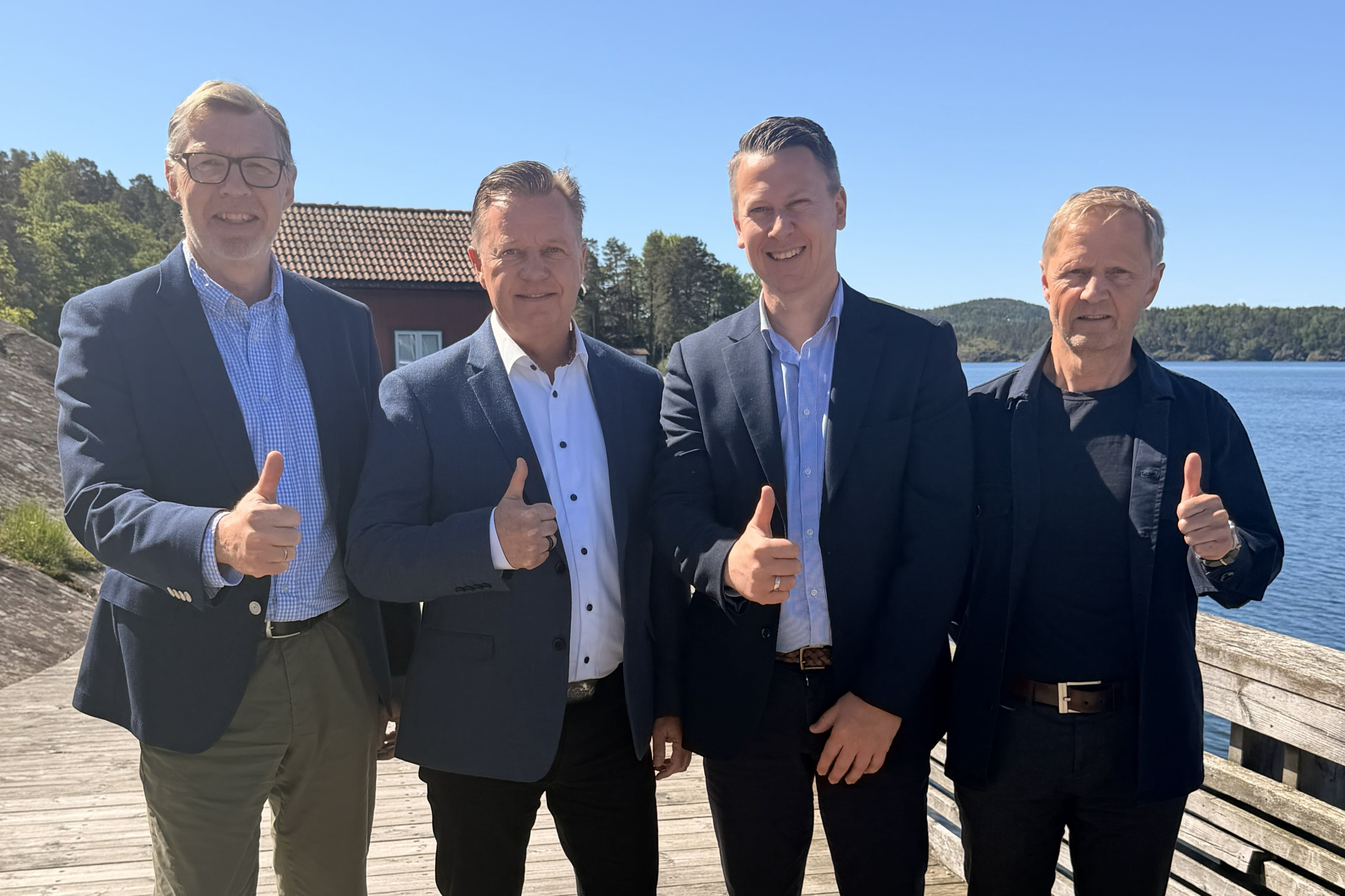 Banksjefene og styrelederne i Berg Sparebank og Trøgstad Sparebank holder tomlene opp og smiler